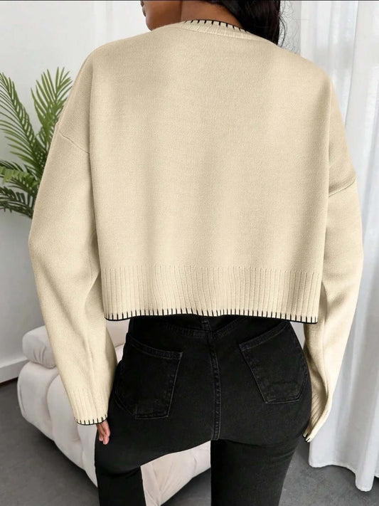 Back view of a woman wearing a cropped loose sweater OEM with black trim, showcasing a stylish knitwear design.