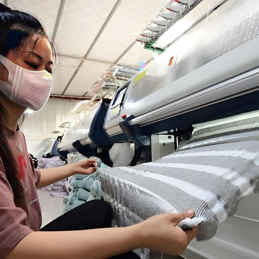 Woman operating a machine while producing knitwear, showcasing the process behind getting an accurate knitwear manufacturer quote.
