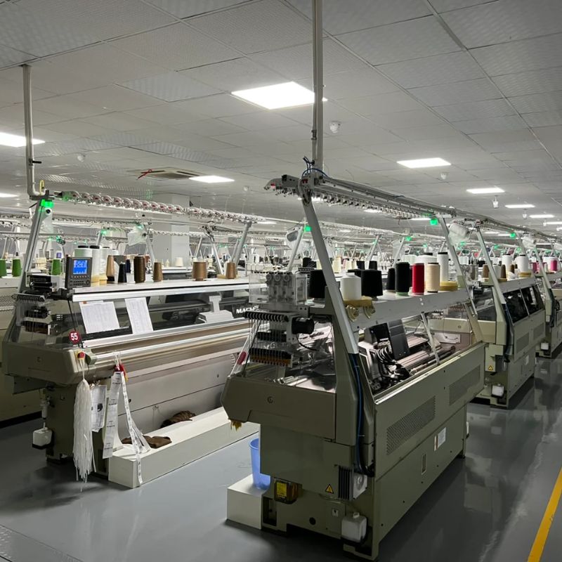 Private label sweater manufacturer in China production facility showcasing knitting machines and yarn.