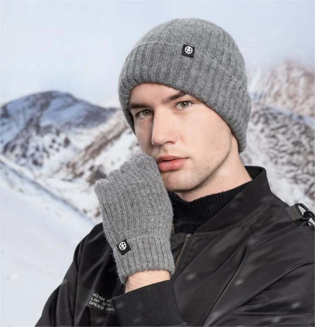 Cold proof hat and gloves set worn by a man against a snowy mountain backdrop.