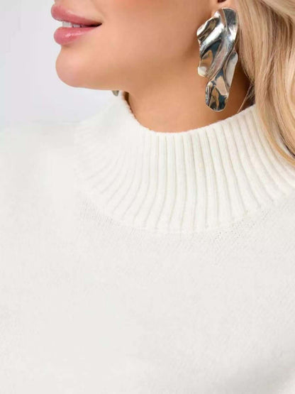 Close-up of a woman wearing a bell sleeve sweater with a mid neck and statement earrings.