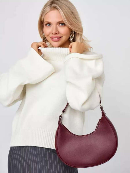 Woman wearing a white bell sleeve sweater with a burgundy handbag, showcasing stylish winter fashion.