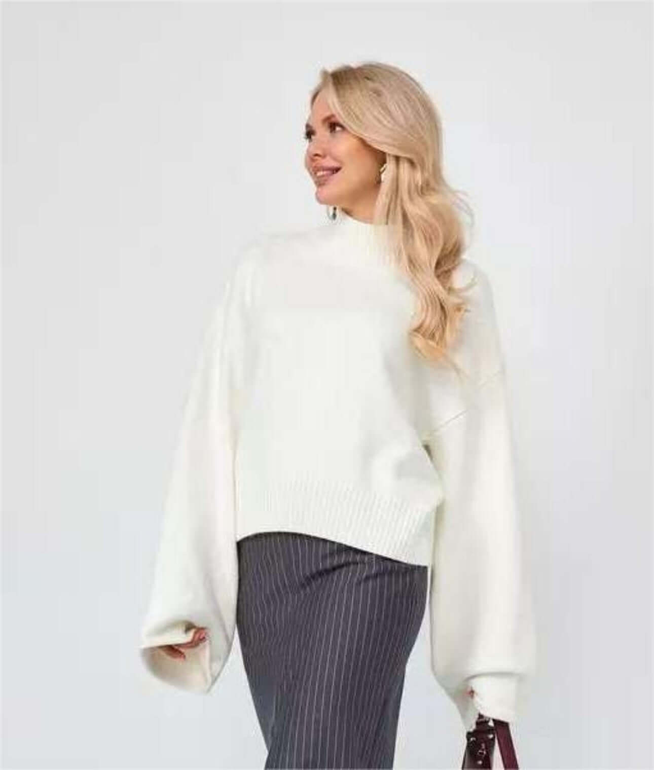 Woman wearing a stylish Bell Sleeve Sweater with mid neck and flared cuffs, paired with striped pants.