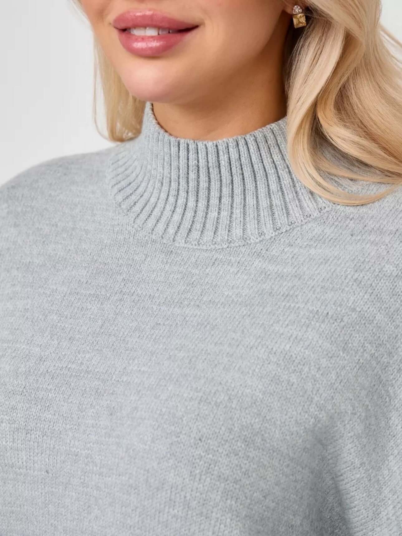 Close-up of a woman wearing a gray Bell Sleeve Sweater with a mid neck and flared cuffs.