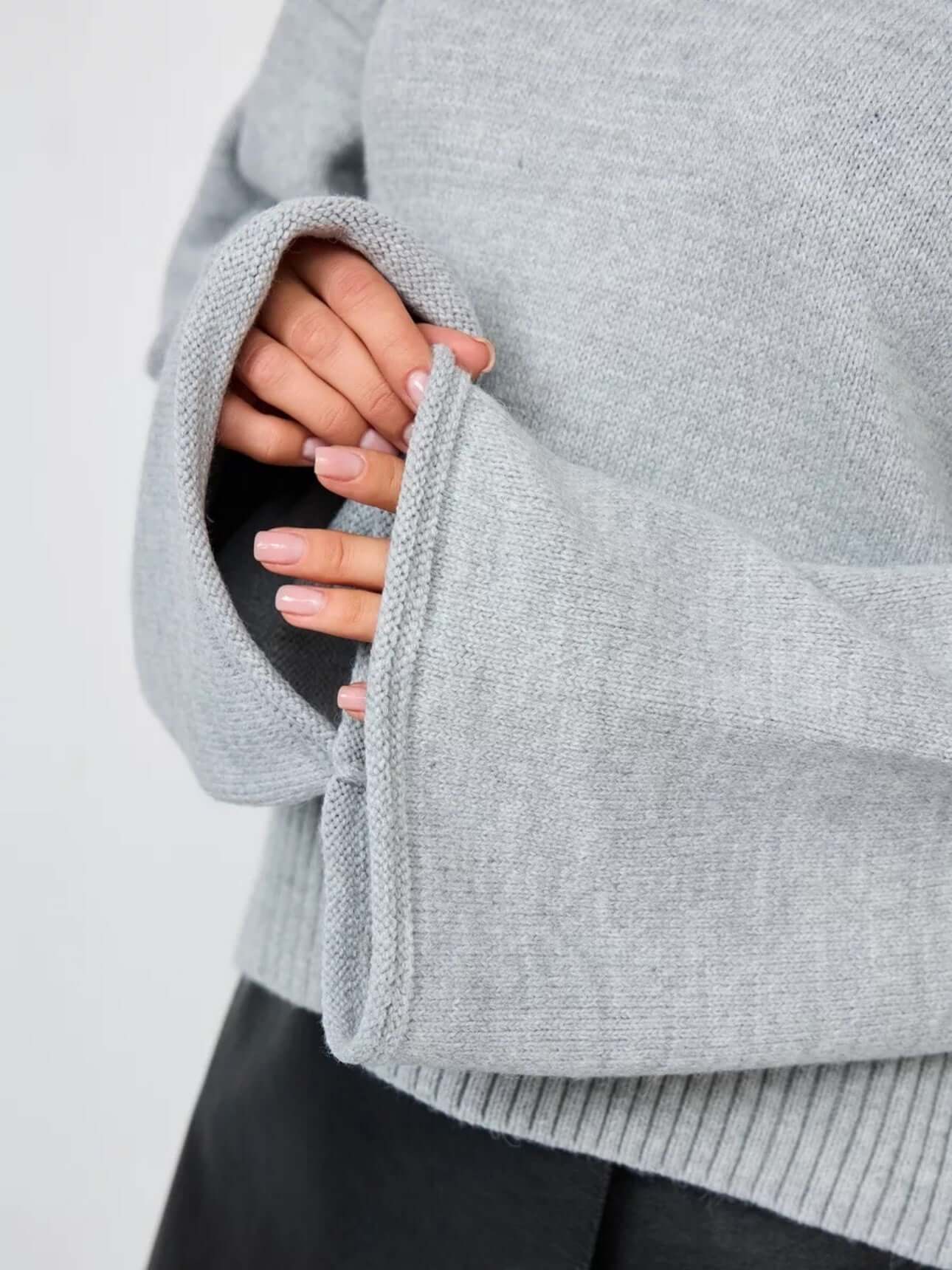 Close-up of women's bell sleeve sweater in gray with flared cuffs and mid neck design.