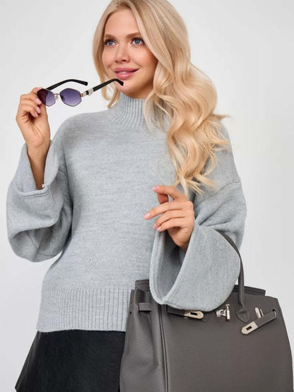 Woman wearing a stylish gray Bell Sleeve Sweater holding sunglasses and a handbag, showcasing the elegance of modern knitwear.