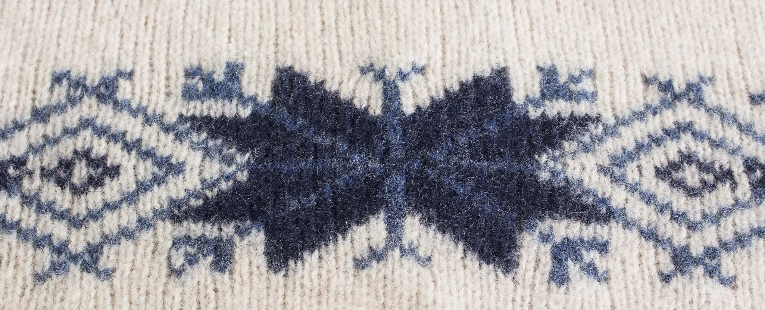 Close-up detail of expert jacquard knitting craftsmanship, featuring our brand promise: Expert Knitwear, Uncompromised Quality.