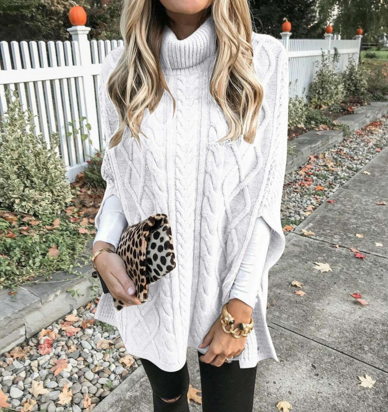 Woman modeling beige high neck cape sweater, front view.