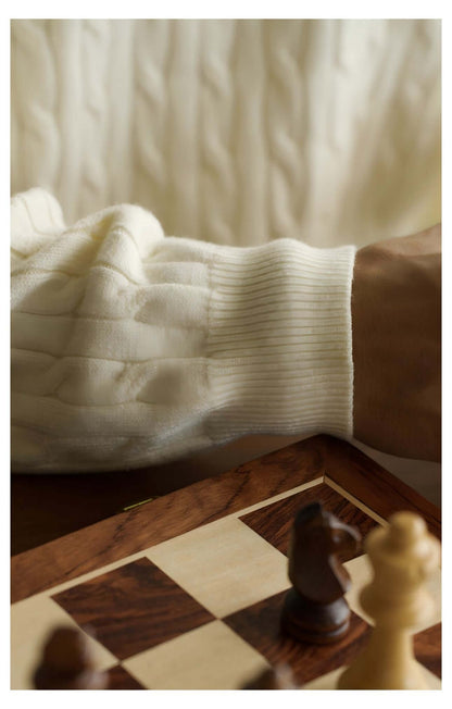 Close-up of a hand in a cream Men's Cable Knit Sweater OEM resting on a chessboard with pieces.