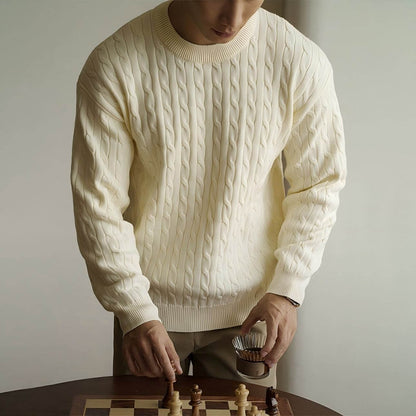Men's Cable Knit Sweater OEM in cream color, styled with Aran patterns, worn by a man at a chess table.