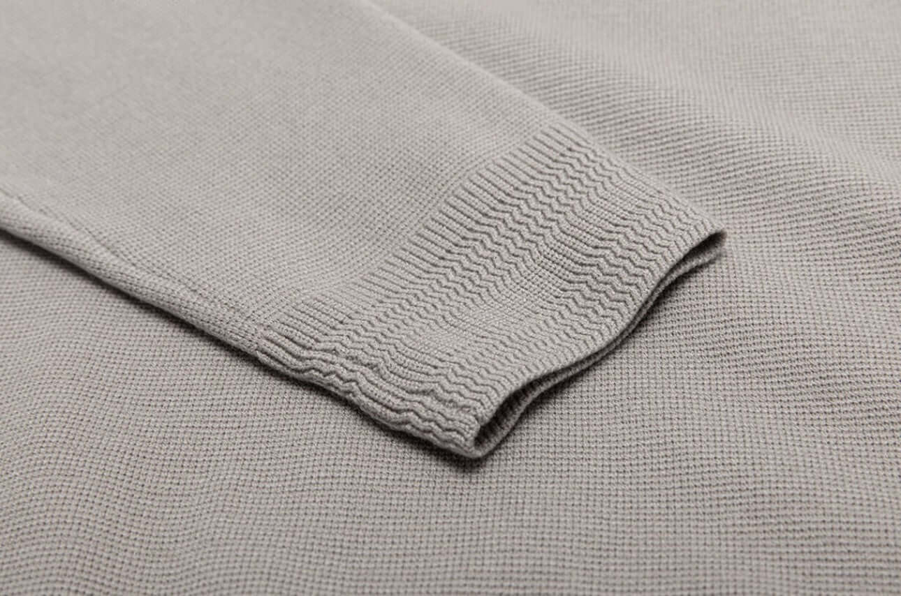 Close-up of the sleeve detailing of a Men's Wool Sweater OEM in light gray, showcasing the knitted texture and ribbed cuff design.