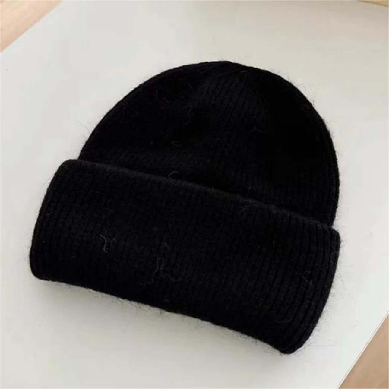 Warm Hat OEM | Black Women's Rabbit Hair Beanie with Folded Brim on a flat surface.